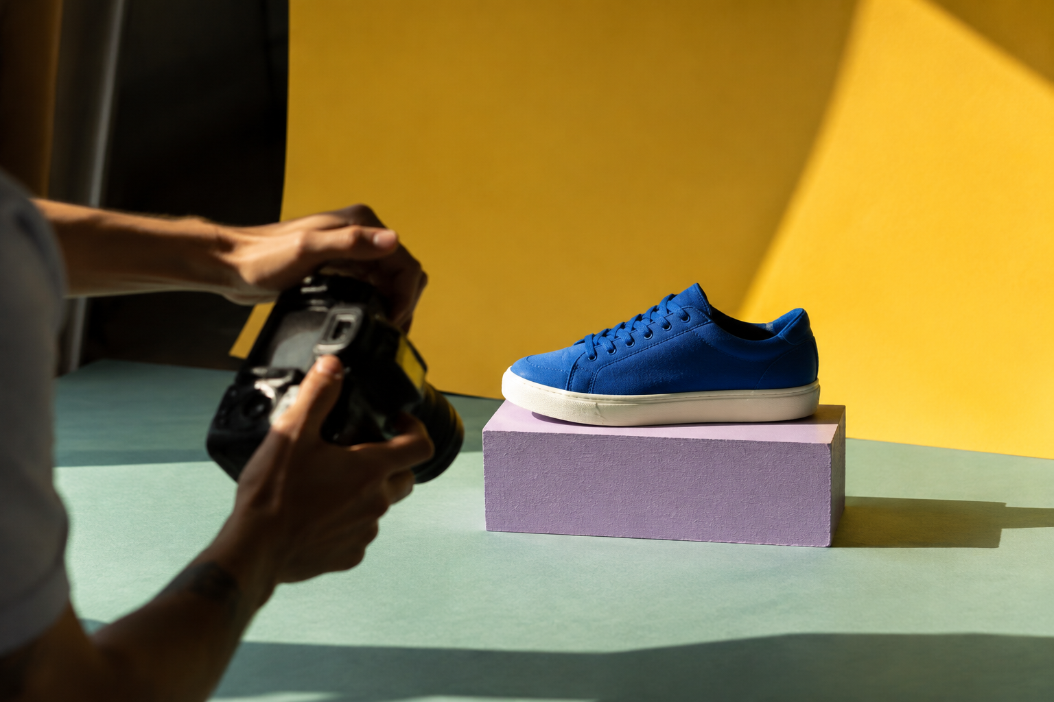 Concept product shoot with a blue sneaker, camera, and colorful studio surfaces
